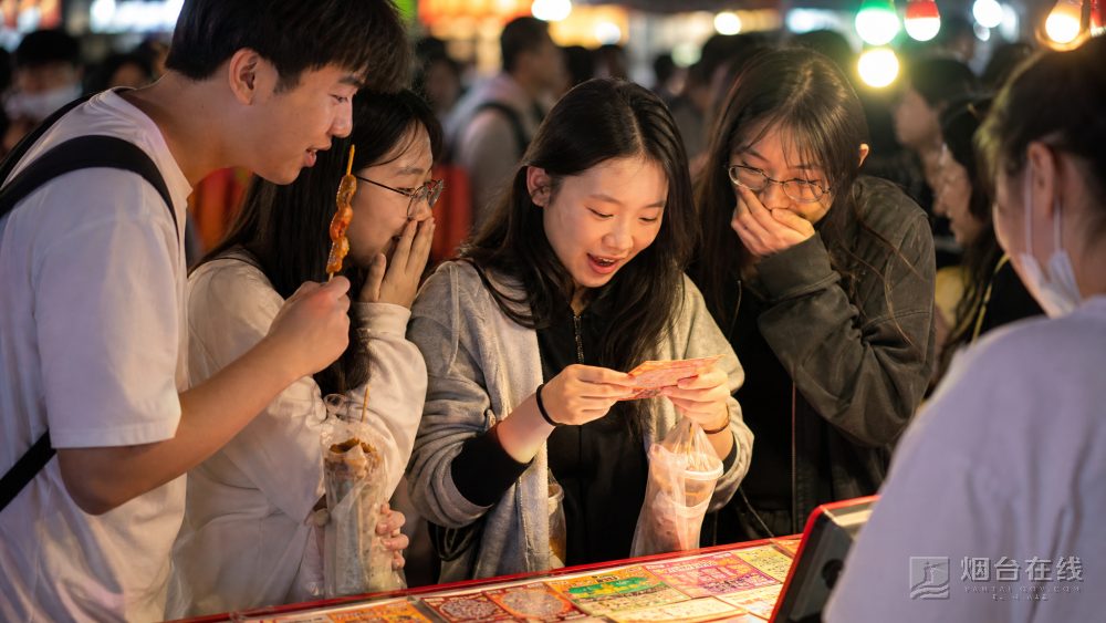 烟台夜市多了刮刮乐摊位，逛完小吃的人顺手试试手气